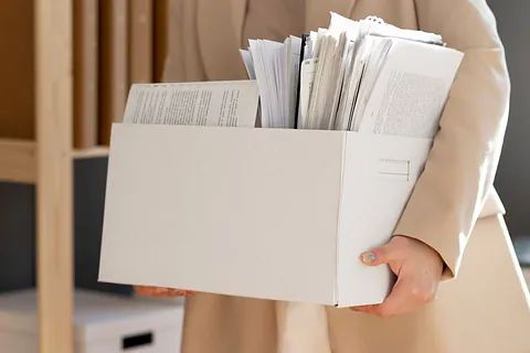 Una mujer sostiene una caja de papeles en sus manos.