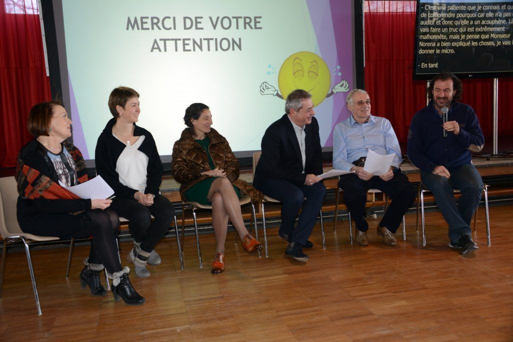 Un panel est assis devant un écran affichant le texte « Merci de votre attention » lors d'un événement public.