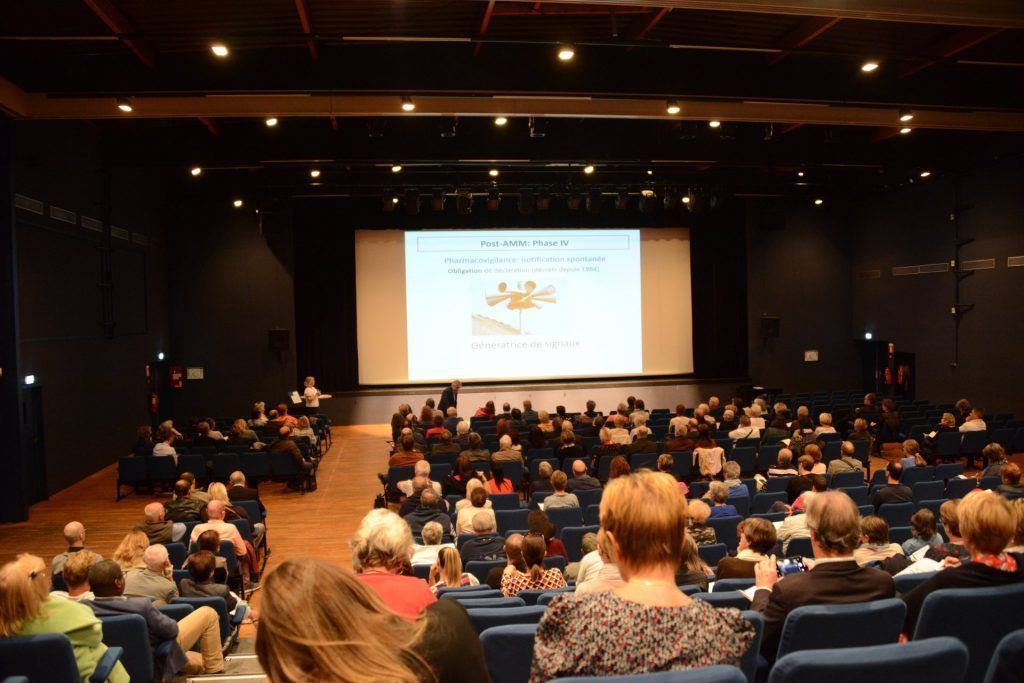 Le public est assis dans une salle de cinéma obscure, regardant une projection sur grand écran.