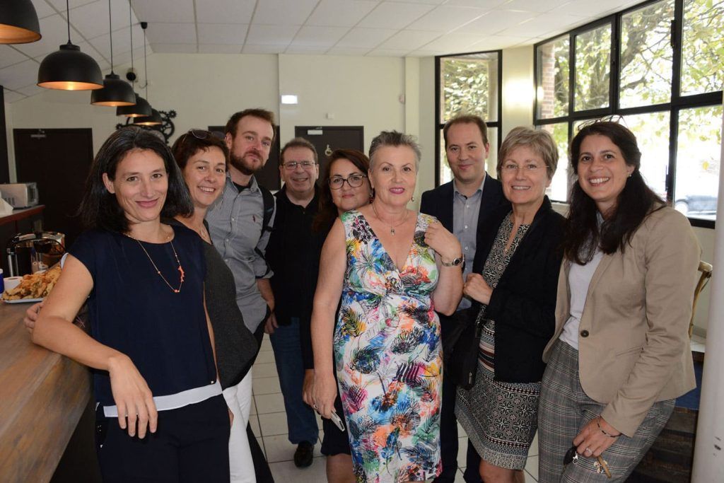 Un groupe de personnes se tient debout à l'intérieur ; elles sourient près d'un bar.