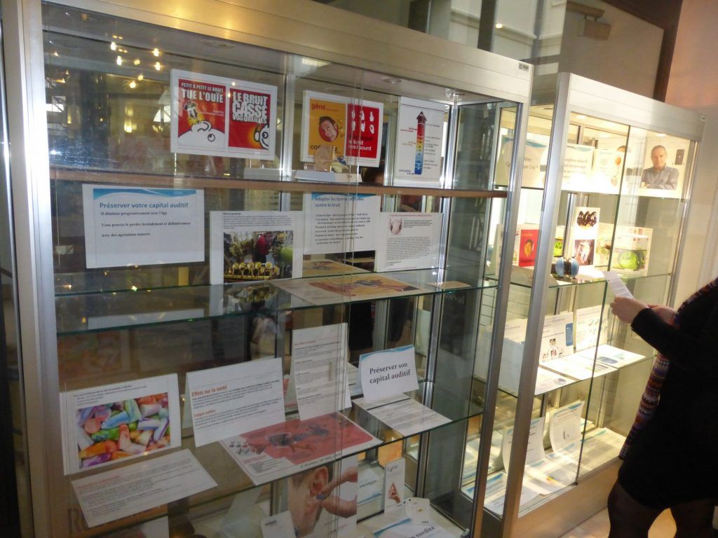 Vitrine contenant des brochures et des œuvres d'art ; une personne tend la main vers la droite.