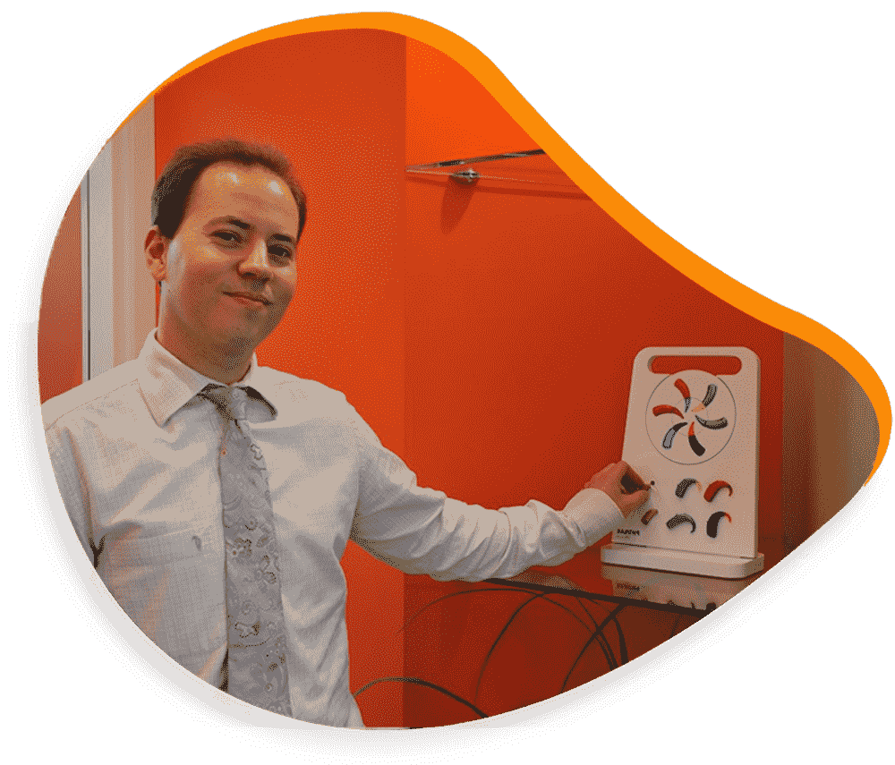 Un homme désigne un appareil blanc orné de formes colorées sur un mur orange.