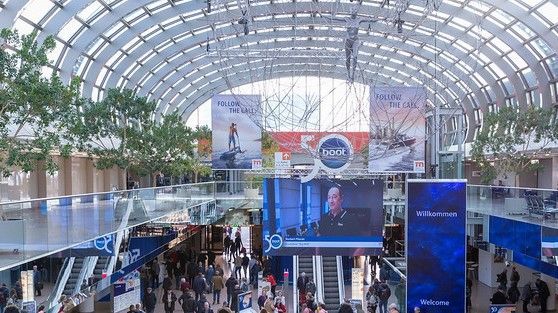 Crowded atrium with a large LED stage and arched glass ceiling at an indoor event