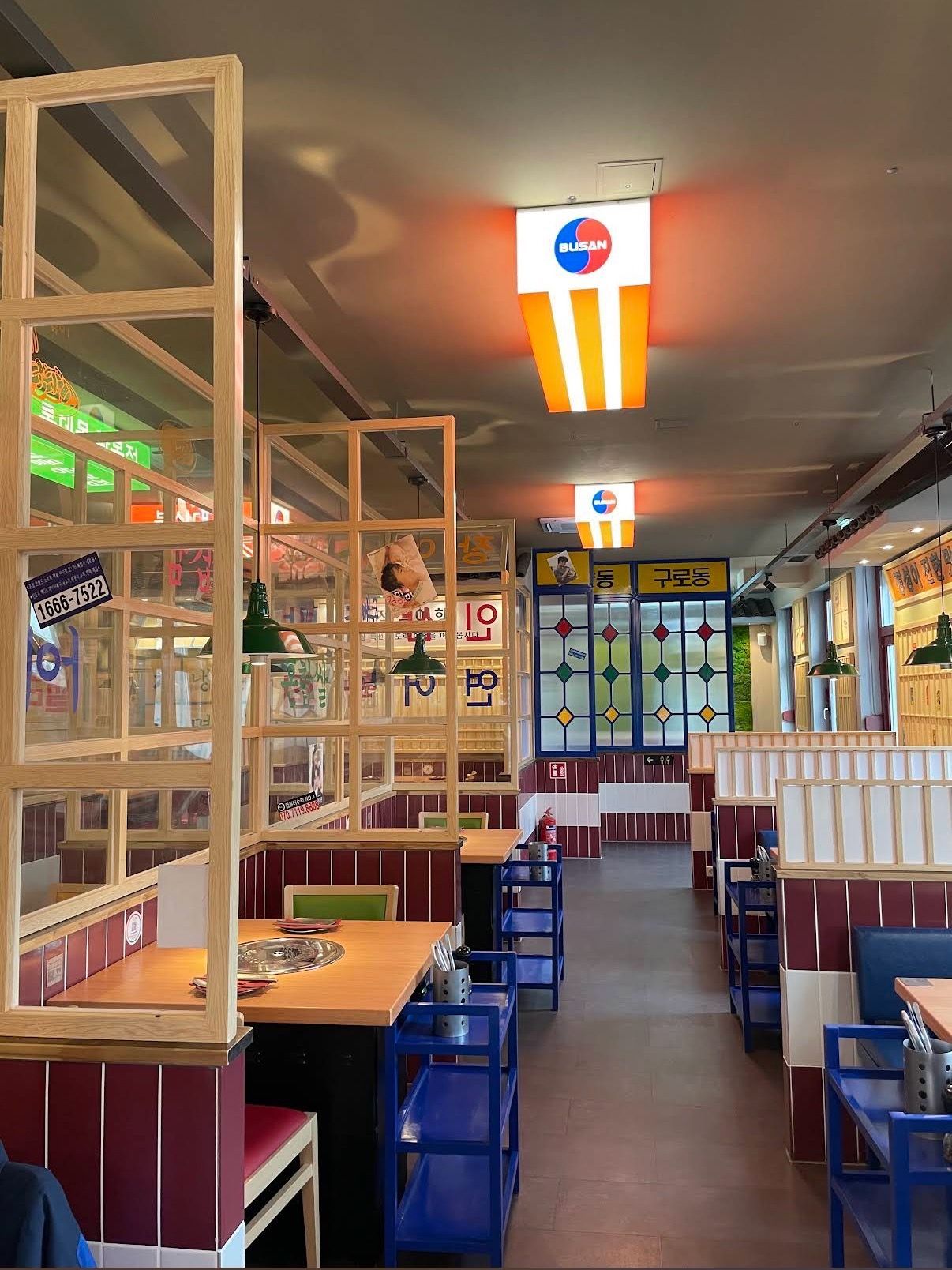 Empty restaurant interior with red booths, wooden dividers, and orange ceiling lights.