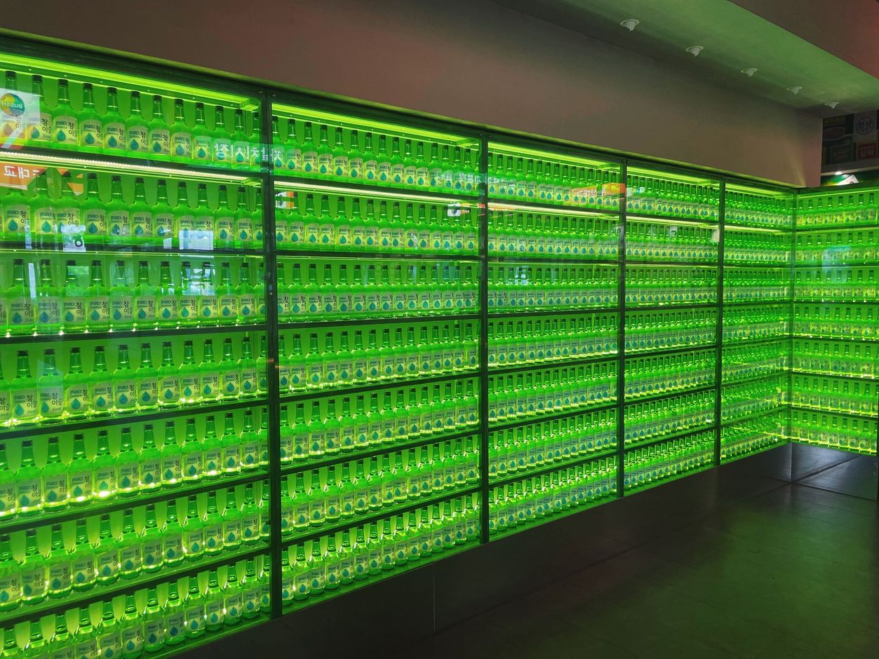 Glowing green wall of stacked bottles in a modern interior, forming a bright illuminated display