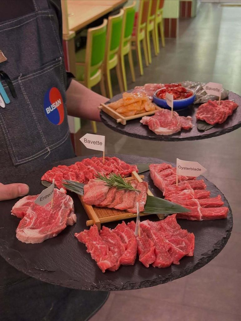 Server carrying plates of assorted raw meat at a Korean barbecue restaurant
