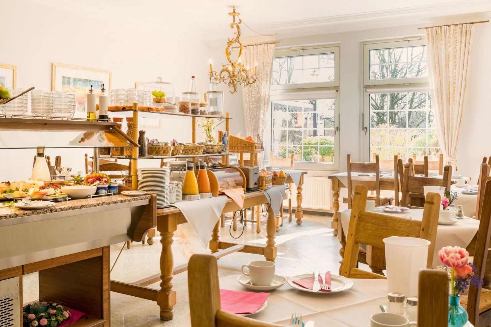 Bright cafe interior with wooden tables, pastries, and sunlight through large windows