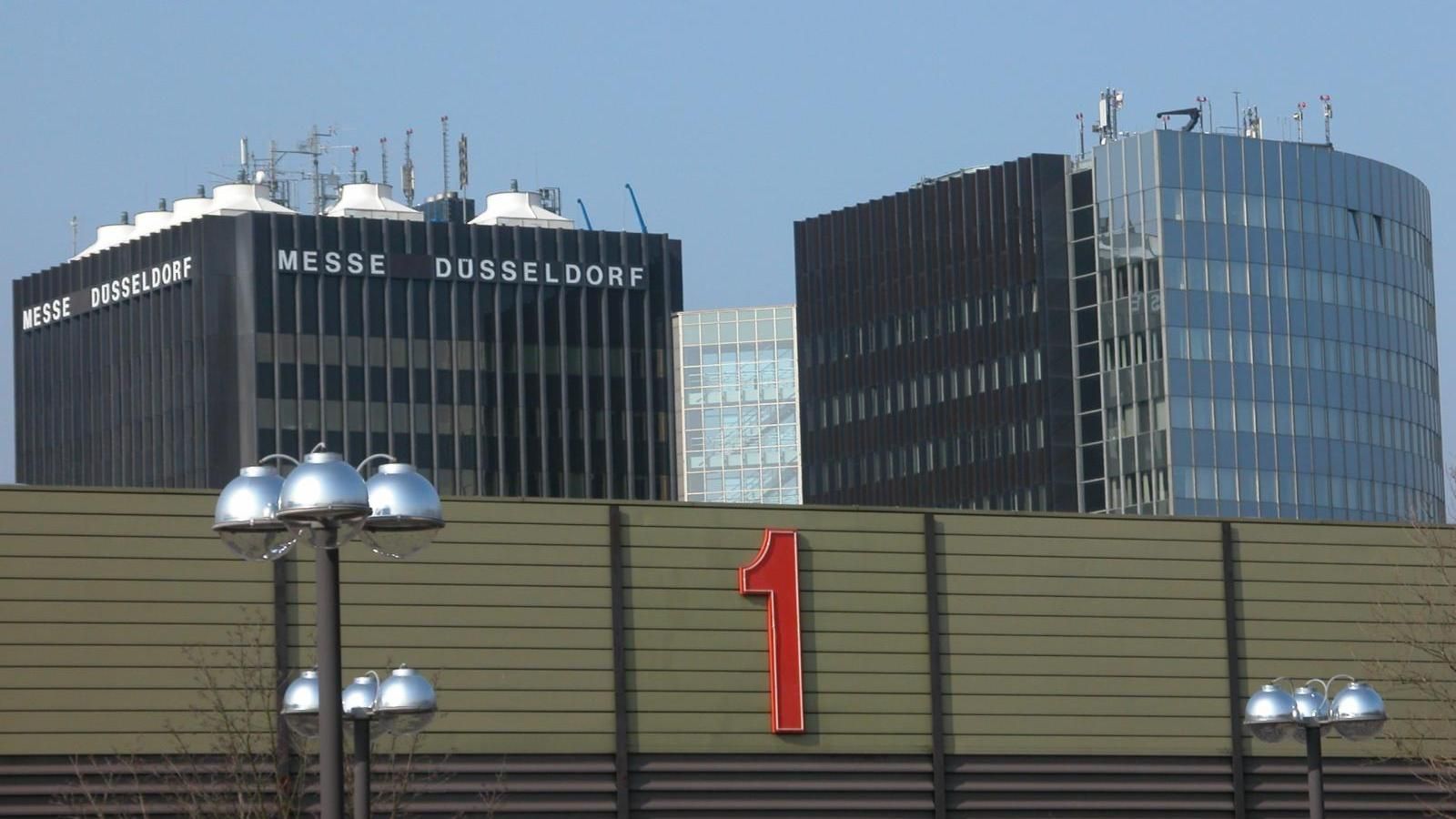 Modern buildings behind a wall with a large red number 1 and street lamps in front