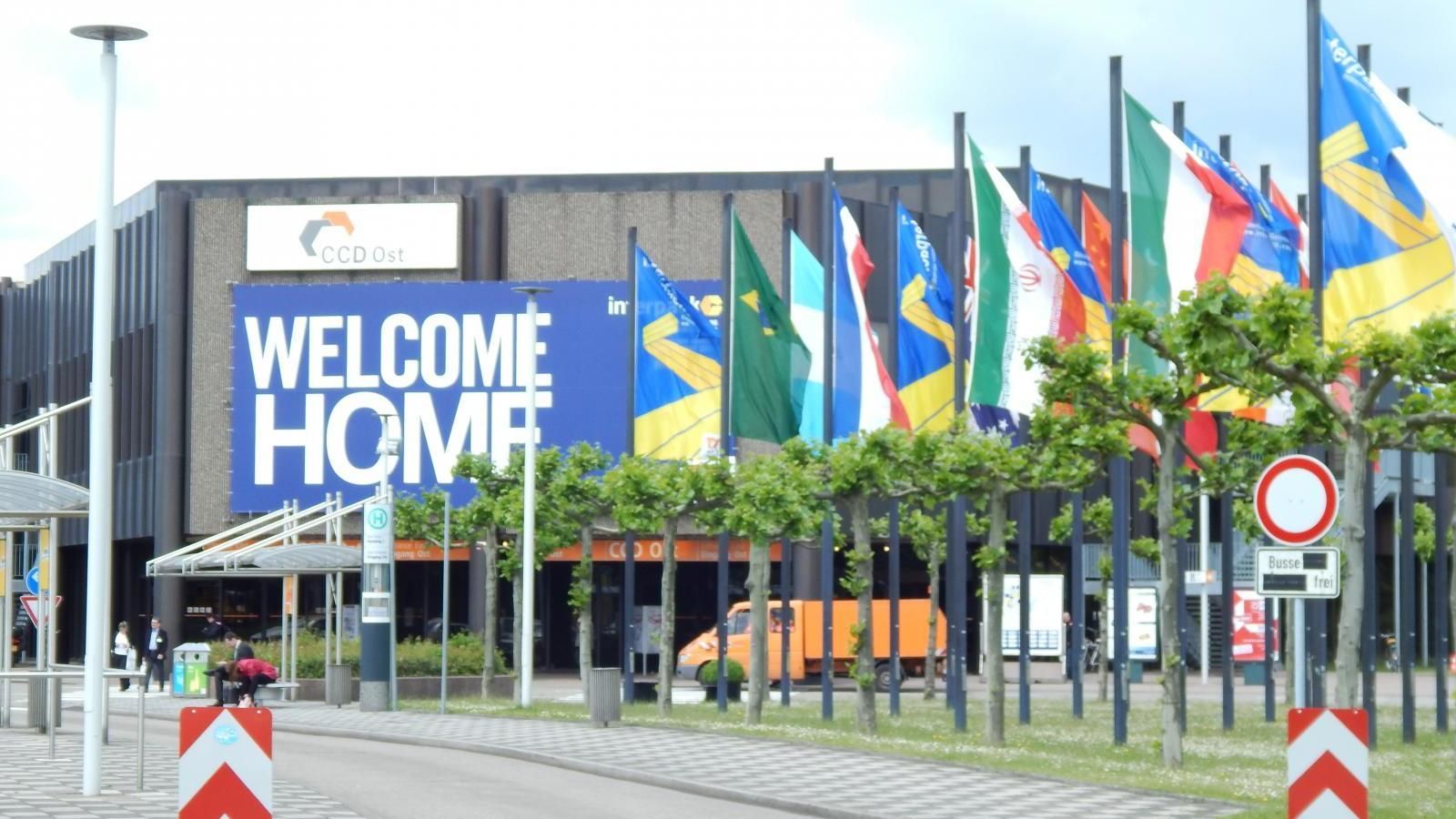 Welcome Home sign beside rows of national flags at a venue entrance