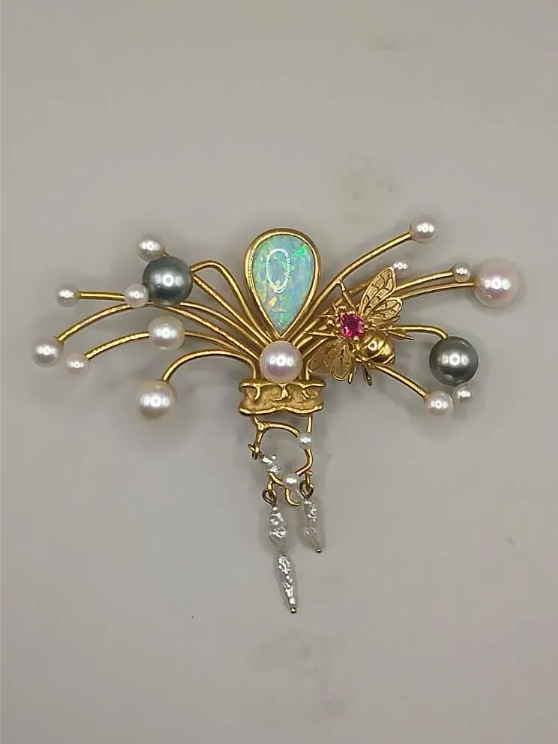 Pendentif en or avec opale, perles et pierre précieuse rouge sur fond clair.