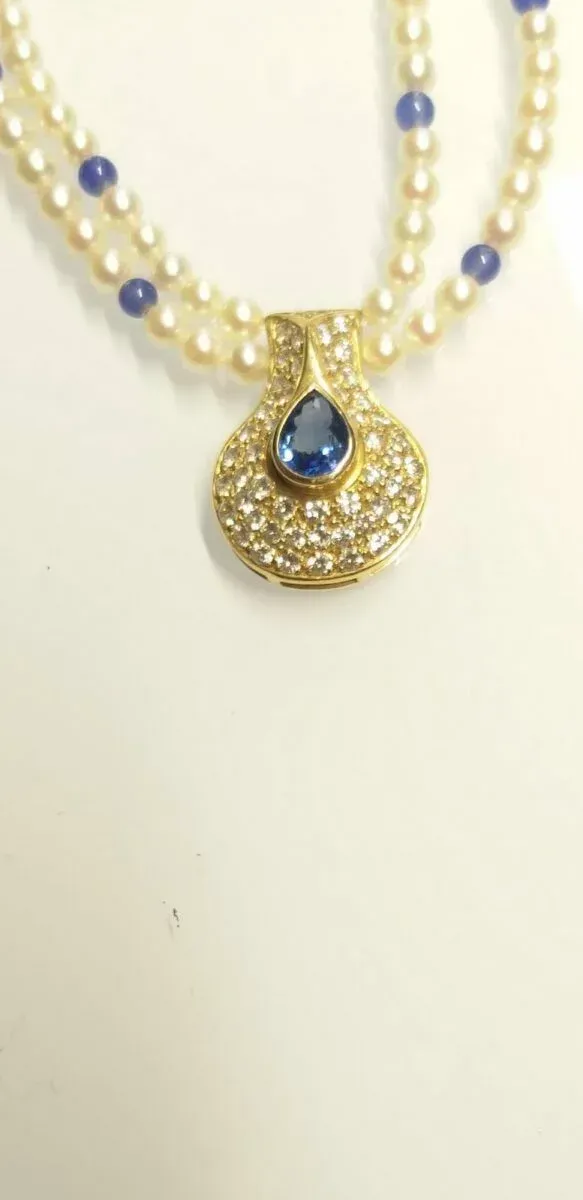 Collier de perles avec un pendentif en or orné d'une pierre précieuse bleue.
