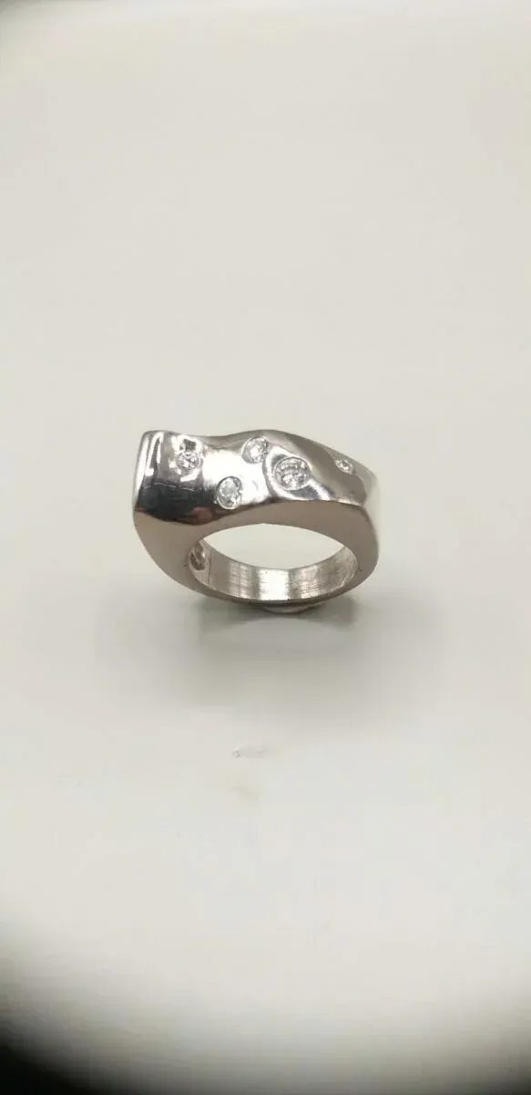 Bague en argent avec motif abstrait et petites pierres.