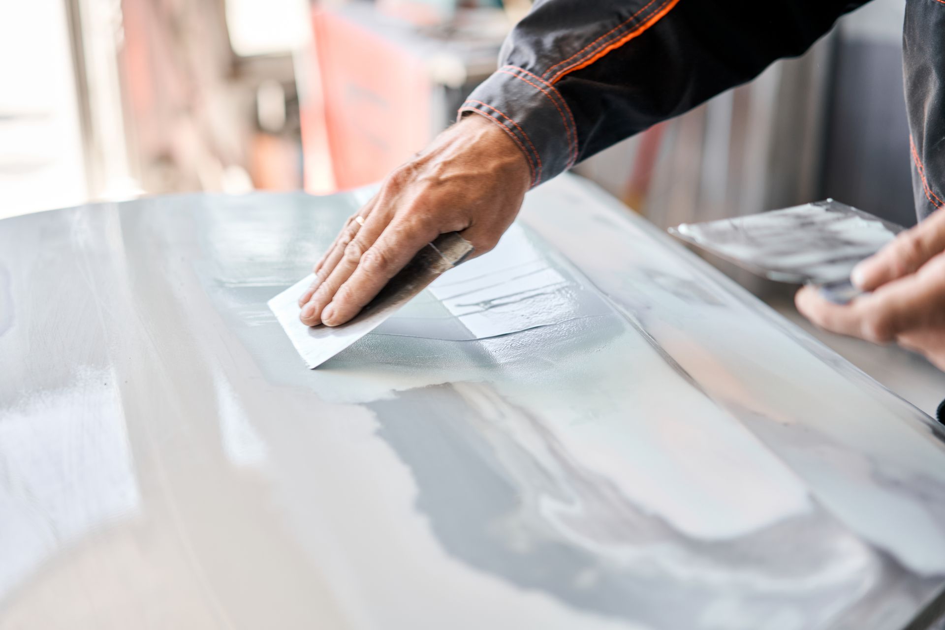 Un garagiste qui applique du mastic sur la carrosserie d'une voiture