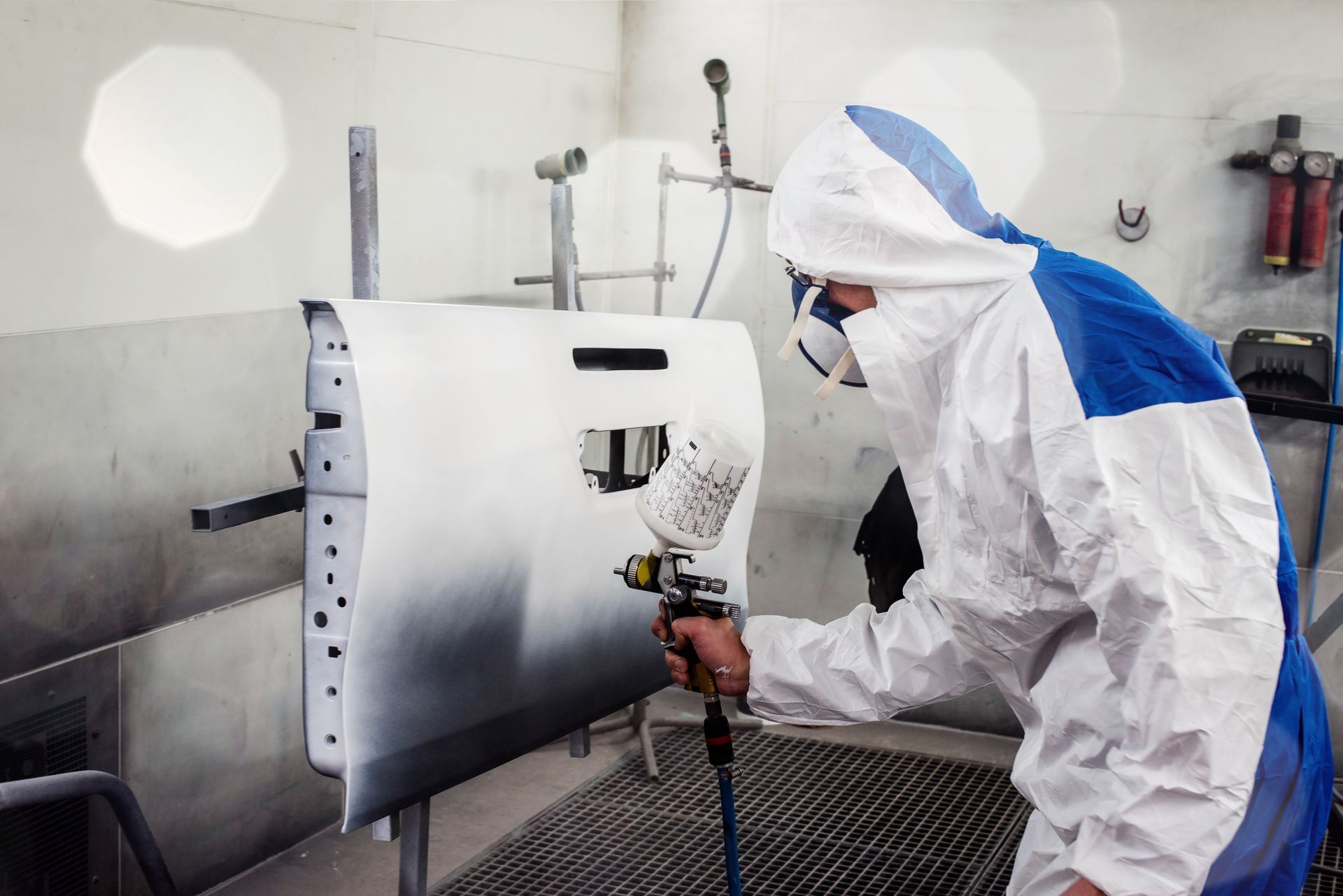 Un peintre automobile qui peint une portière en blanc