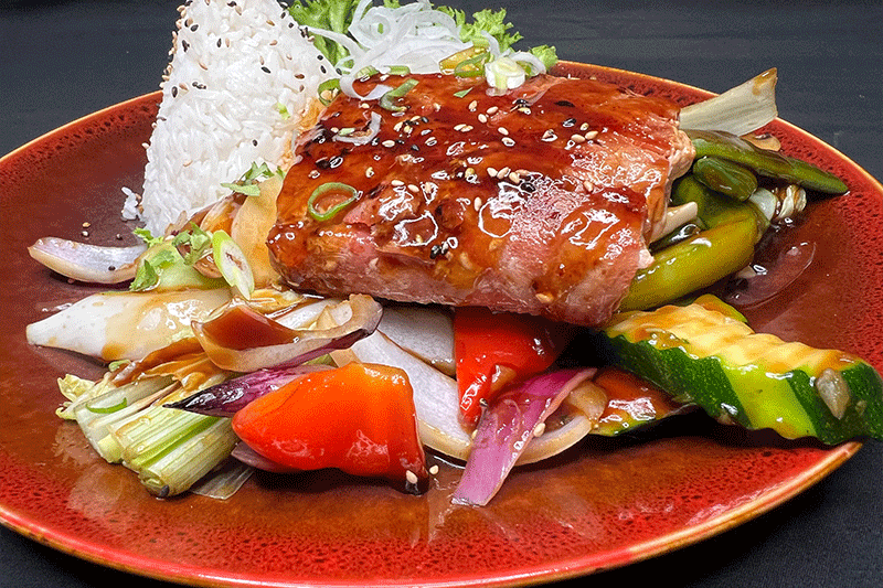 Ein langer Holztisch mit Tellern, Weingläsern und Kerzen darauf.