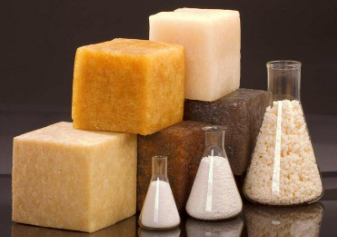 Varias pastillas de jabón y pequeños recipientes de vidrio llenos de sales o polvos de baño sobre un fondo oscuro.
