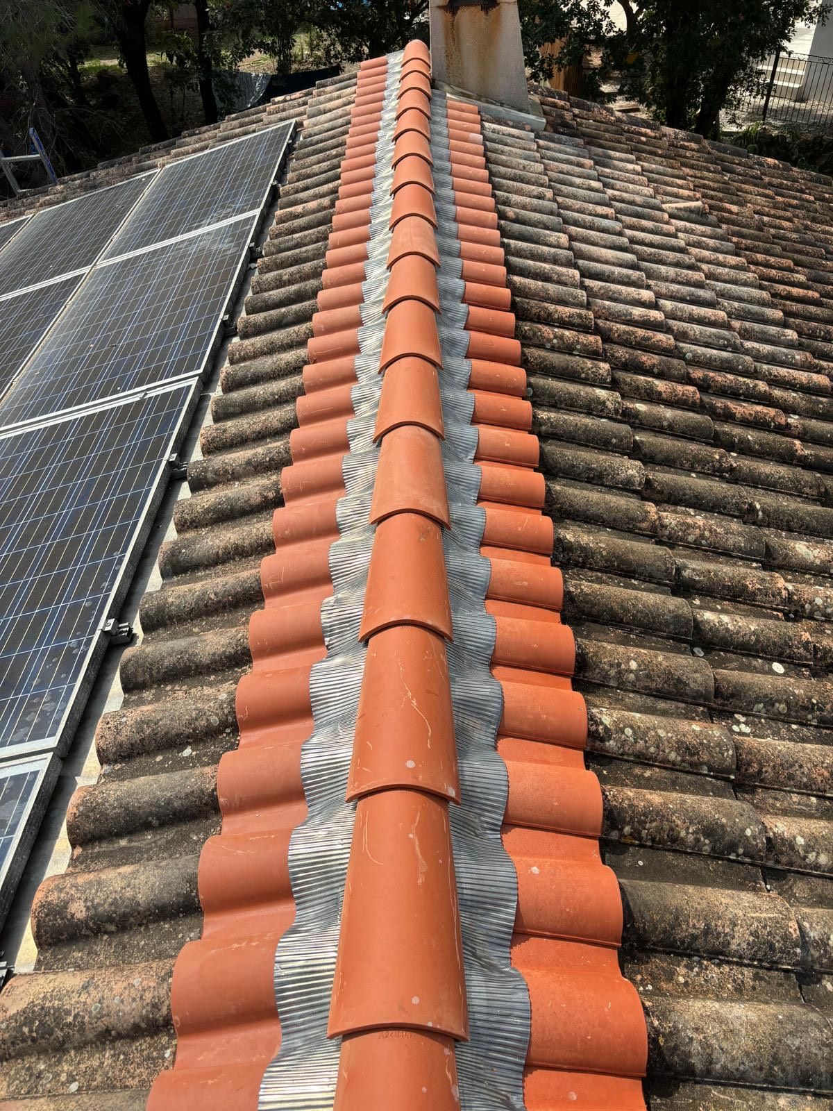 Un toit avec beaucoup de tuiles et des panneaux solaires dessus.