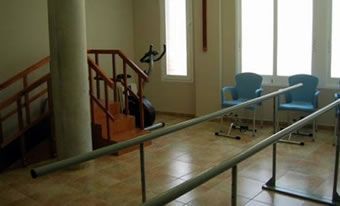 Una habitación con escaleras, barras, sillas y una bicicleta.