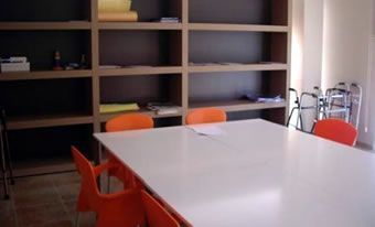 Una habitación con una mesa blanca y sillas naranjas.