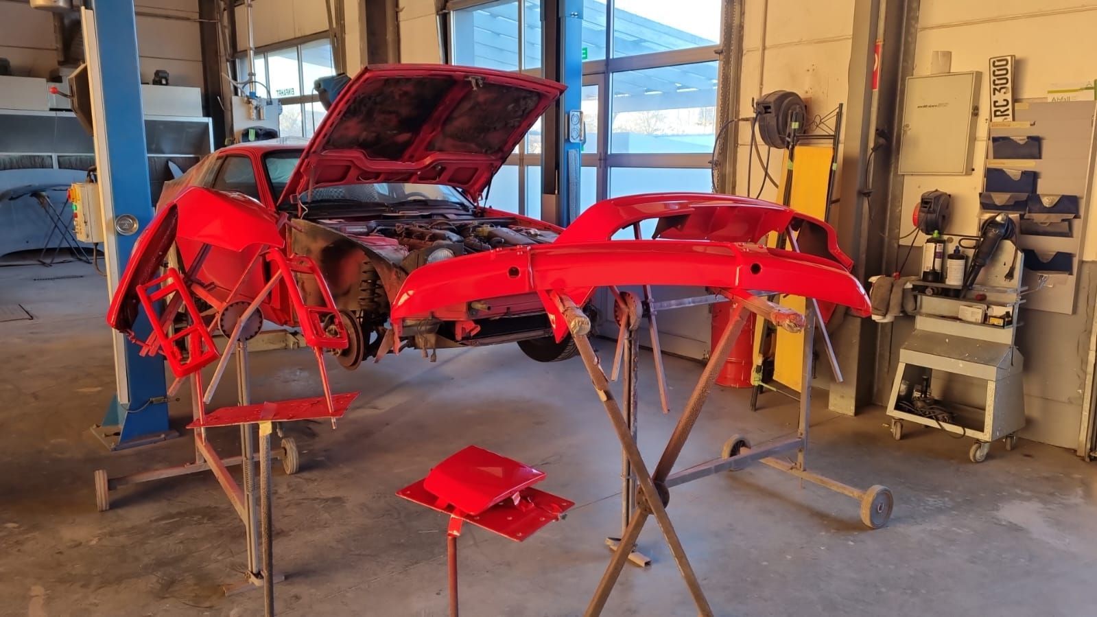 In einer Garage wird ein rotes Auto lackiert.