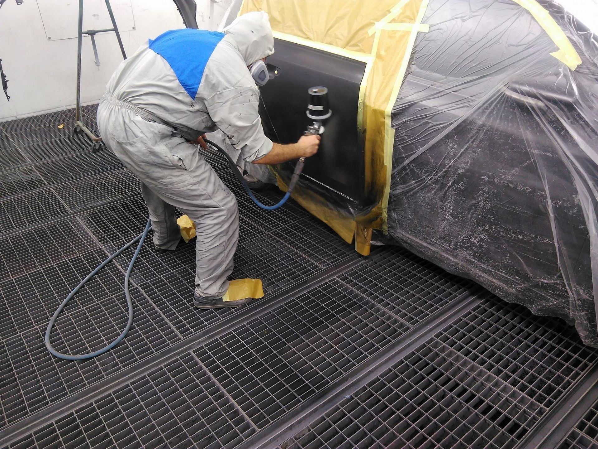 Ein Mann im Schutzanzug streicht eine Autotür.