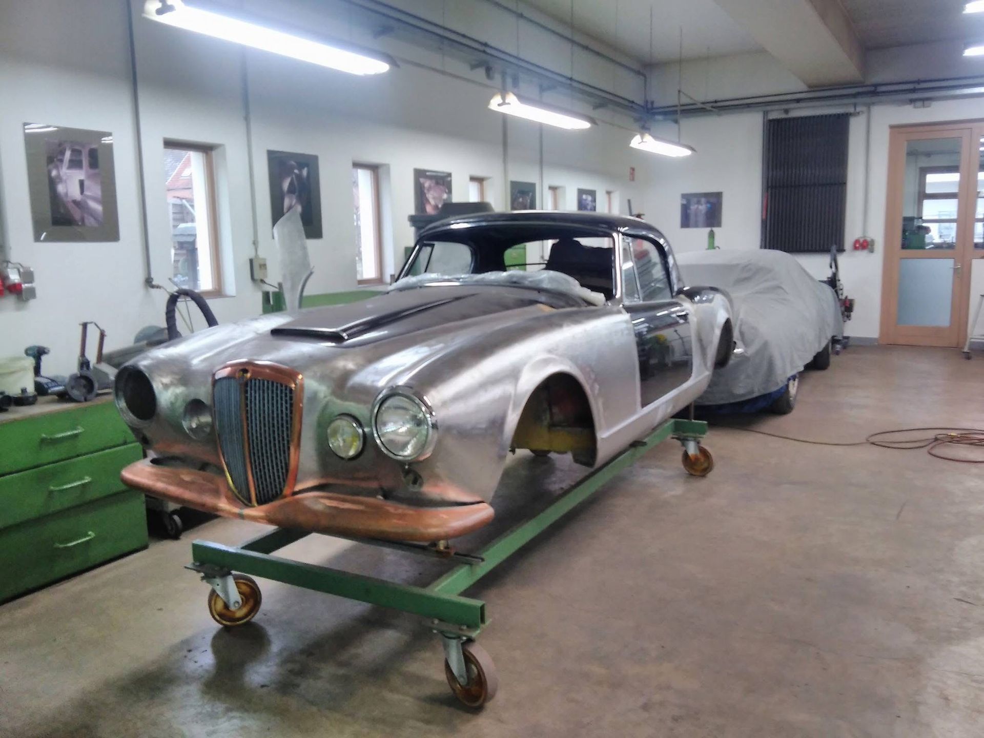 Ein Auto steht auf einem grünen Wagen in einer Garage.