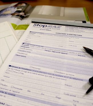 Gros plan sur un formulaire de contrat de maintenance StopGAZ posé sur un bureau, avec un stylo posé sur le papier.