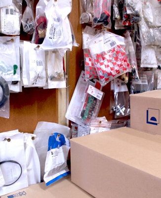 Un entrepôt ou une réserve encombrée, avec des étagères remplies de divers petits produits dans des sacs en plastique transparents et des boîtes en carton.