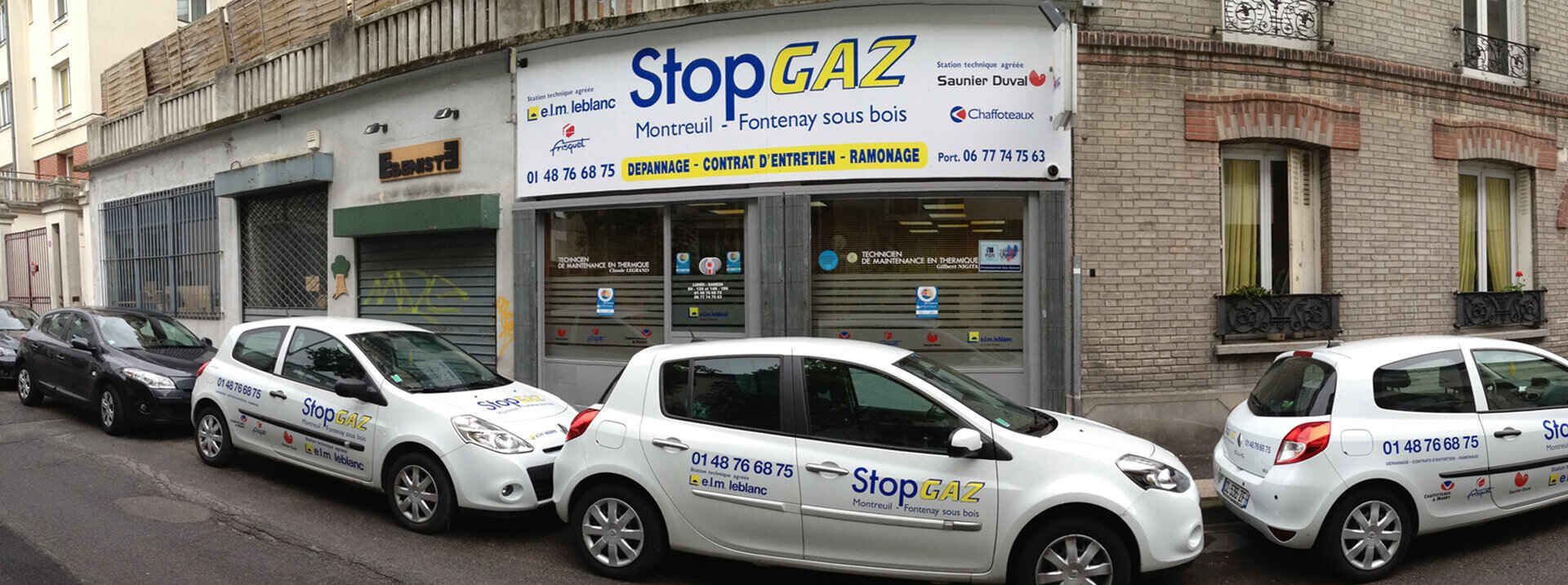 Trois véhicules blancs portant les initiales de la marque étaient stationnés devant un magasin appelé Stop Gaz, dans une rue.