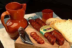 Una tabla de cortar de madera cubierta con salchichas, pan y una jarra.