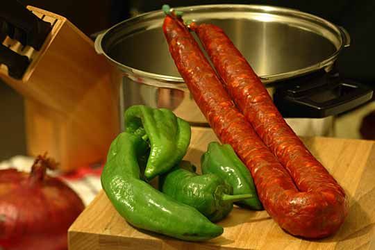 Una tabla de cortar con pimientos verdes y salchichas encima.