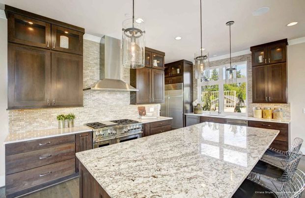 Küche mit dunklen Holzschränken, Geräten aus Edelstahl und einer Arbeitsinsel aus Granit.