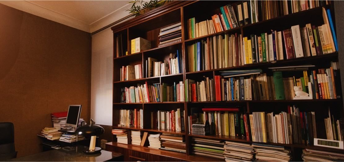 Estanterías llenas de libros en una biblioteca o sala de estudio acogedora, revestida de madera