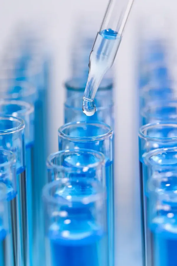 Pipette zum Abfüllen blauer Flüssigkeit in Laborreagenzgläser in einer wissenschaftlichen Umgebung