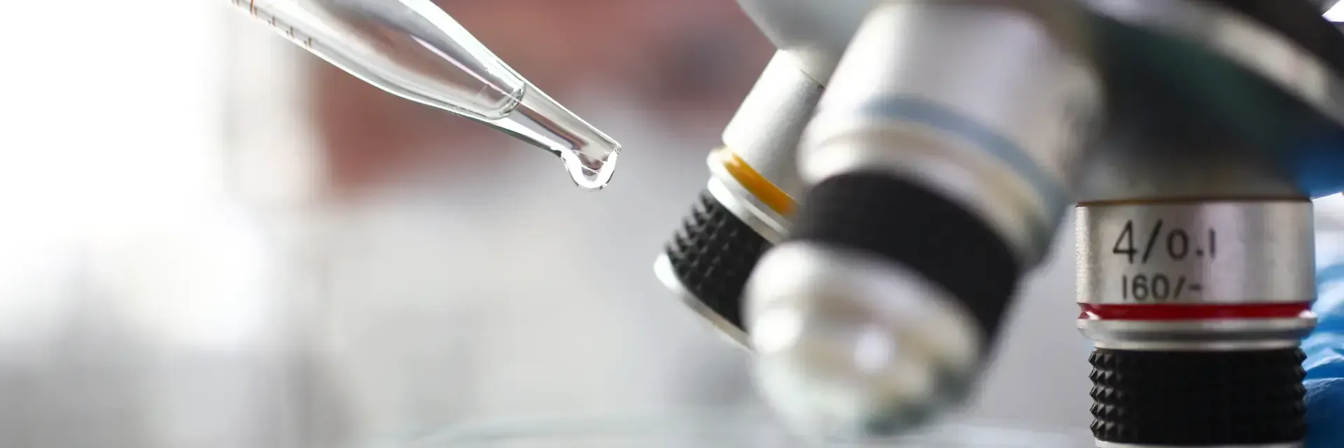 Laborpipette neben Mikroskop und Reagenzgläsern in einer hellen wissenschaftlichen Umgebung