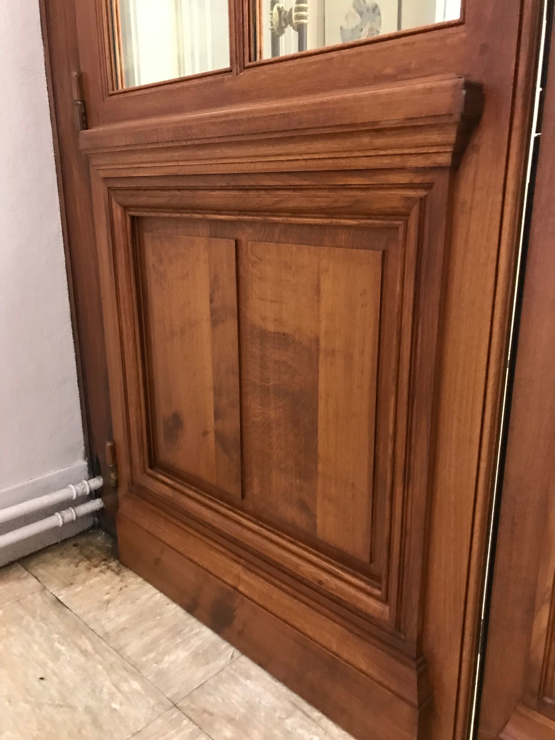 Entrée de maison blanche avec porte d'entrée noire, auvent et boîte aux lettres. Toit gris, boiseries blanches.