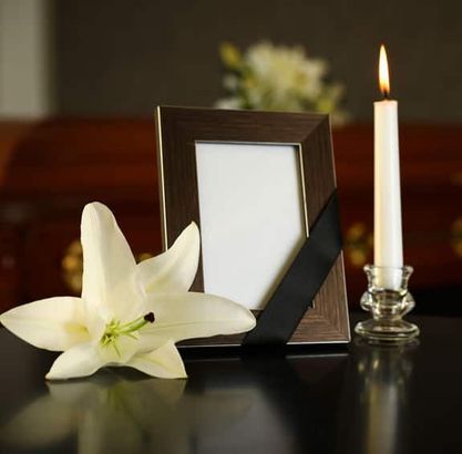 Un marco de fotos con una cinta negra y una vela sobre una mesa.