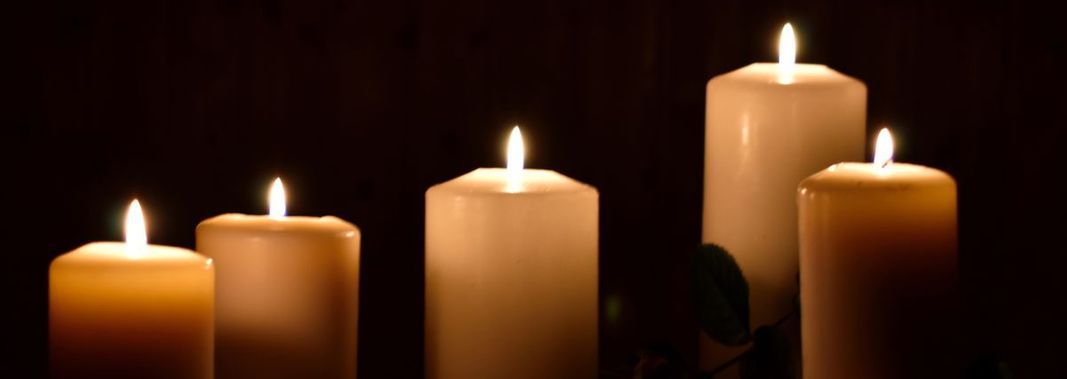 Un grupo de velas están encendidas en una habitación oscura.