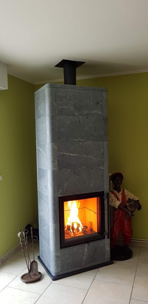 Poêle à bois Tulikivi de couleur gris foncé avec mur de couleur vert pomme derrière