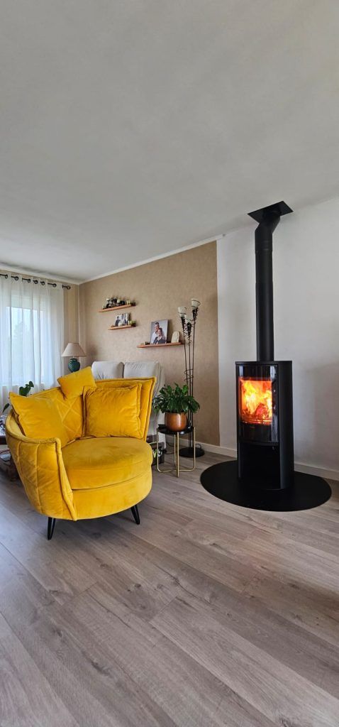 Poêle à bois dans un salon avec fauteuil jaune devant