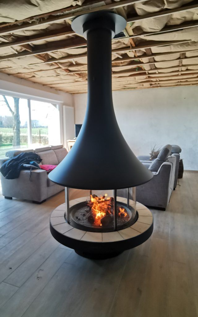 Cheminée de forme arrondie au milieu d'un salon avec foyer bois