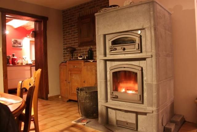 Poêle à bois en pierre ollaire Mammutti de Tulikivi de forme rectangulaire avec foyer allumé dans un salon