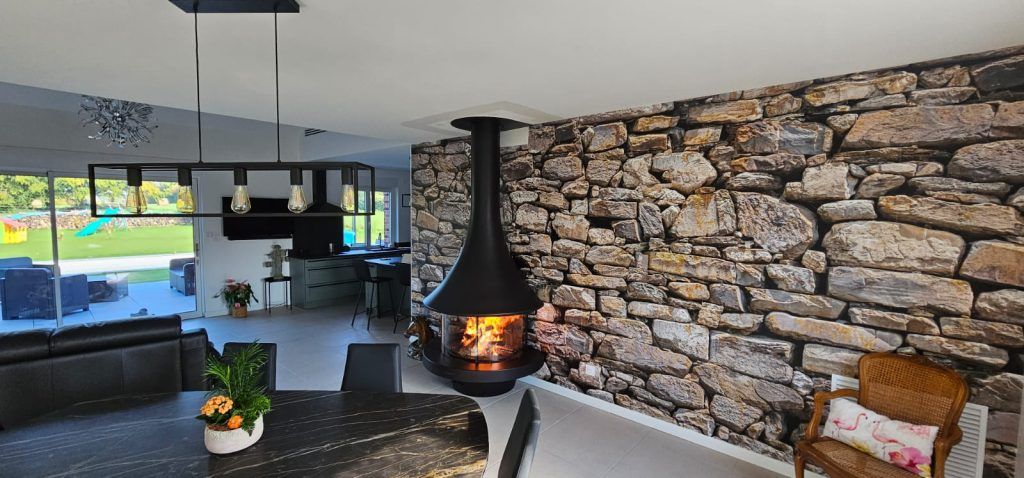 Cheminée suspendue noire avec mur de pierre en fond