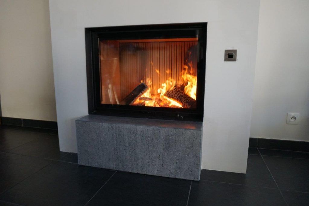 Zoom sur le foyer de l'insert dans un mur blanc avec un support gris en dessous