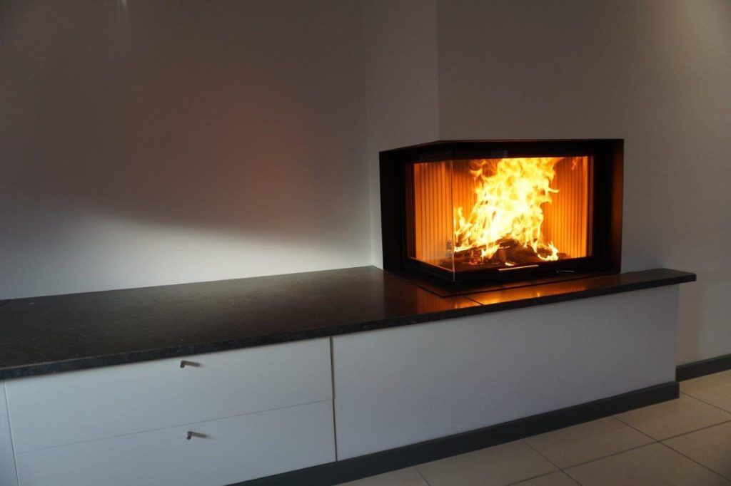 Zoom sur le foyer de l'insert bois incrusté à droite d'un renfoncement dans le mur d'un salon