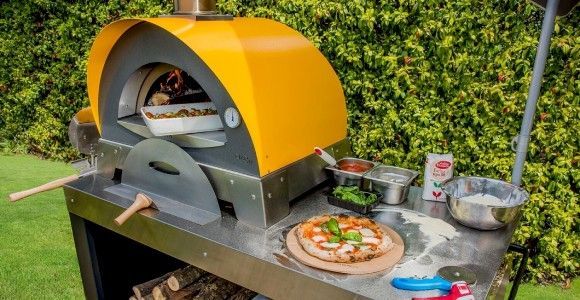 Four à pizza Alfa forni de couleur jaune en train de cuire un grattin au feux de bois