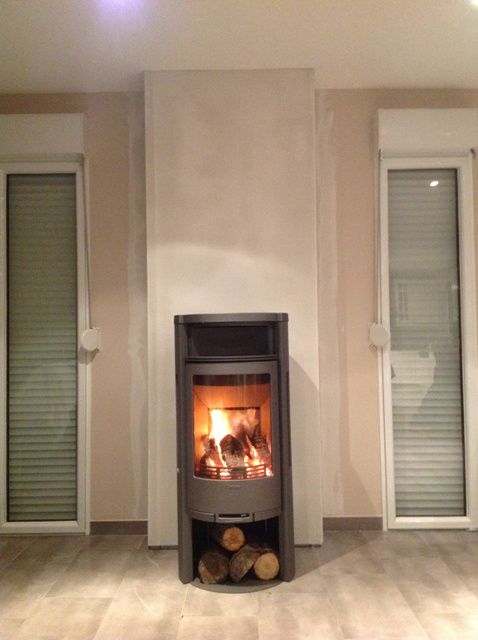 Poêle à bois de forme arrondi avec réserve de bois en dessous