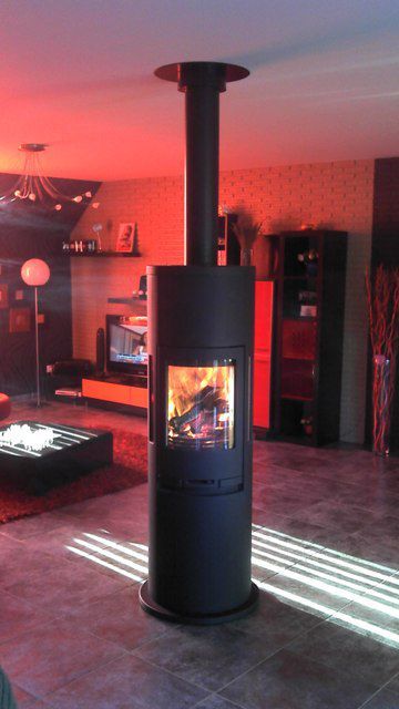 Poêle à bois noir devant au milieu d'un salon avec éclairage rouge en arrière-plan