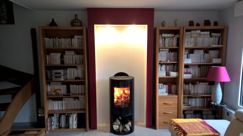 Poêle à bois de forme arrondi de couleur noire au milieu d'une bibliothèque