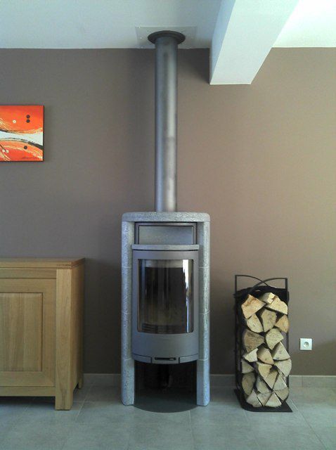 Poêle à bois gris de forme rectangulaire gris et réserve de bois sur le côté